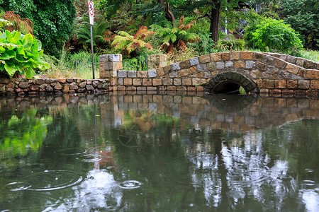 池塘上方的石拱桥背景图片