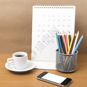 咖啡 电话 日历和彩色铅笔职场办公室桌子商业记事本木头笔记白色杯子文档背景图片