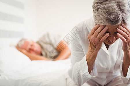 坐在床上的丧心病狂的年长妇女高清图片