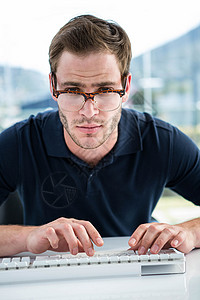 使用计算机的帅哥电脑显示器男人屏幕电脑电子键盘眼镜桌子办公室旋转椅背景图片