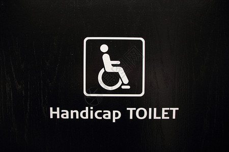 白色残疾残疾人厕所在黑木上的标志背景图片
