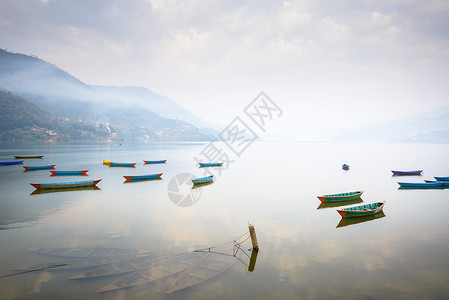 三桅帆船尼泊尔波克拉的Phewa湖钓鱼帆船支撑三桅风景多云独木舟山脉蓝天场景背景