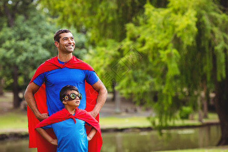 你是我的超级英雄父亲和儿子穿着超级英雄服装男性英雄俏皮眼镜乐趣男生男人公园面具家庭背景