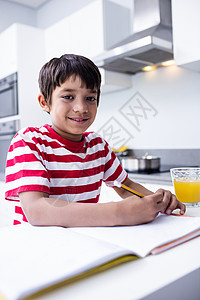 男孩在厨房做功课瞳孔橙汁童年房子学习家庭作业混血男性学校休闲背景图片