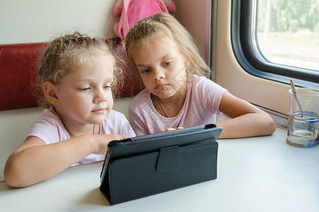两个女孩坐在火车上 看着一个卡通在盘子里背景图片