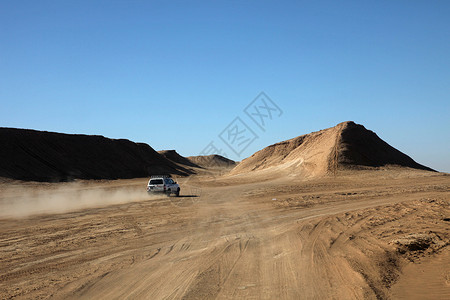陆地巡洋舰沙漠中的汽车阴影驱动游客运输沙景旅行车辆驾驶灰尘旅游背景