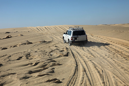 陆地巡洋舰沙漠中的汽车旅行沙景灰尘游客天空农村假期驱动旅游车辆背景