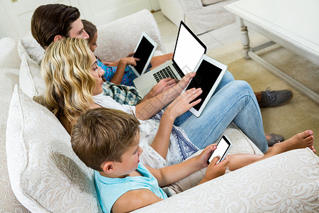 家庭坐在沙发上时使用各种技术的家庭背景图片
