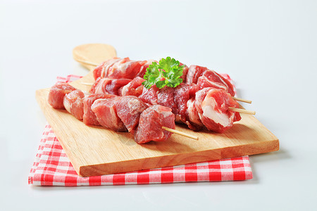 原猪肉叉餐巾烤串食物砧板检查食材红色背景图片