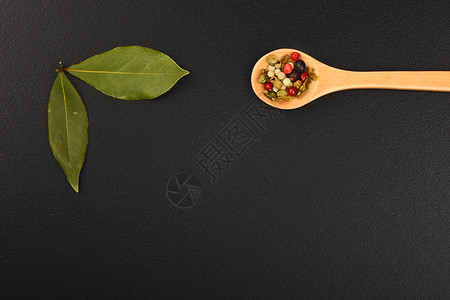 两个海湾叶子和黑黑粉笔板上的胡椒桂冠调味品黑板粉笔勺子木板烹饪黑色香料胡椒子背景图片