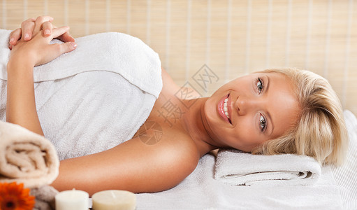 在温泉中心放松的年轻女子护理水疗成人享受水平微笑女性美容毛巾身体背景图片