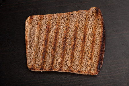 木制桌上的烤黑麦面包面包黑色早餐食物桌子鸟瞰图生产油炸炙烤条纹背景图片