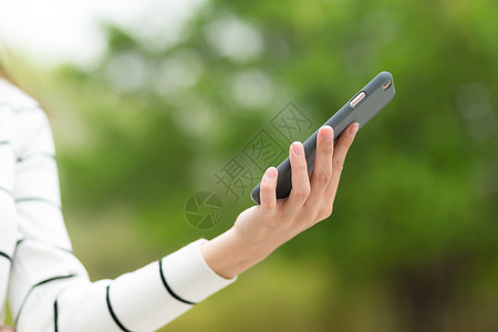 妇女在公园使用手机的情况绿色女士细胞游戏短信身体冲浪阅读电话女性背景图片