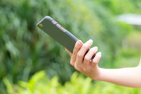 妇女使用手机绿色公园植物电话游戏女孩冲浪女性女士短信背景图片