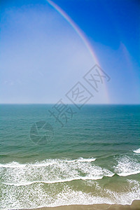 海滩海岸岸上多彩彩彩虹蓝色雷雨天空场景波浪海岸线海洋支撑背景图片