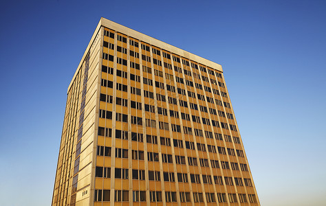 蓝色天空上的旧式摩天大楼阳光中心晴天会议建筑学橙色结构办公楼复古水平背景图片