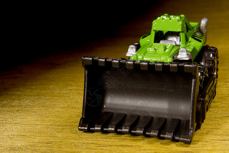 亮光塑料爆破玩具卡车工业车辆机器绿色木头机械童年挖掘机黑色背景图片