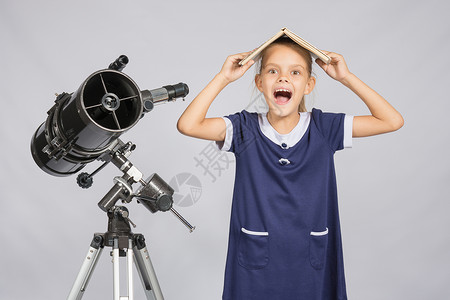 女学生用教科书蒙住她的头 哭喊着看着框架 站在望远镜旁站立背景