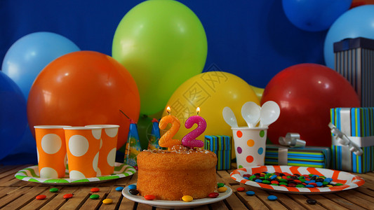 气球盒在土气木桌上的生日蛋糕有五颜六色的气球 礼物 塑料杯子和塑料盘子的背景有糖果和蓝色墙壁的在背景中周年火焰塑料杯幸福桌子蛋糕惊喜盒背景