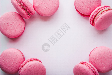 白桌布上的粉红马卡龙饼干椭圆形杏仁白色框架烘烤粉色背景图片