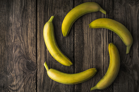旧木制桌上的绿香蕉背景图片