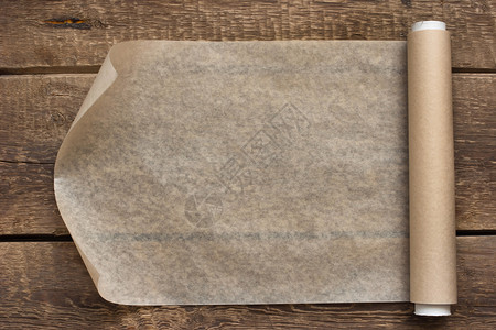 木制表格背景上的一张开放的纸卷场地白色棕色木头桌子滚动黑色羊皮纸背景图片