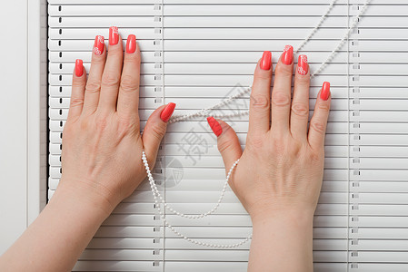 女用手在窗边擦指甲和百叶窗阳光房间办公室风格女性商业塑料窗户装饰建筑物背景图片