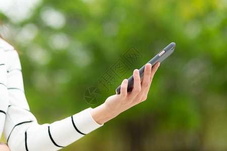 妇女在公园使用手机的情况绿色女孩游戏冲浪短信女性阅读电话细胞身体背景图片