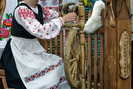 年轻女人在旋转轮上转动线纺纱羊毛操作土布乐器说明织工艺术纺纱机男人背景图片