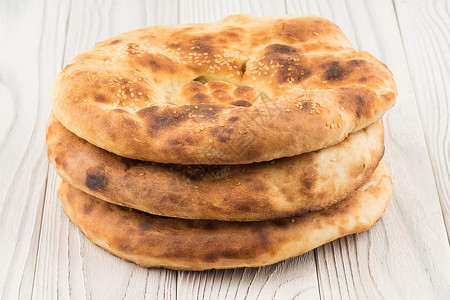 乌兹别克面包在旧白木桌上食物木板木头产品烘烤包子早餐小吃白色芝麻背景图片