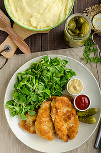 配马铃薯泥和沙拉的Schnitzel油炸面包屑盘子猪肉土豆蔬菜香菜美食鱼片牛扒背景图片