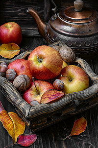 秋季苹果和坚果季节红色乡村茶会核桃收获叶子篮子黄色桌子背景图片