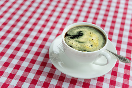 在白瓷杯子中的黑咖啡桌布织物飞碟白色茶匙饮料背景图片