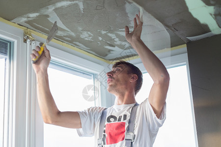 修补室内墙壁和天花板的粉刷控制板装修画家石膏工人职业涂层工作承包商梯子背景图片