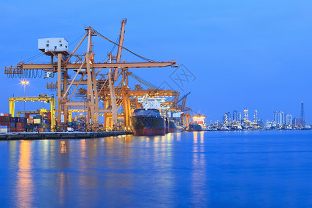 在美丽的暮色中 有重型起重机的造船厂海洋海岸港口船运蓝色商业码头出货商品世界背景