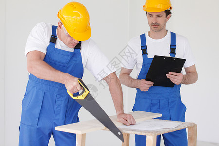 工人锯木板男性安全帽团队工作帽子文档承包商职业工作服建设者背景图片