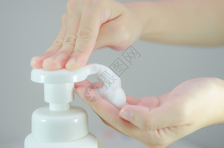 扎鞭子将鞭子泡沫肥皂放在手上清洁剂瓶子香波液体卫生消毒用品手指洗剂喷出背景