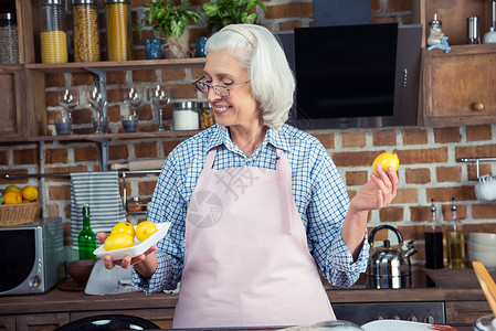 妇女看厨房的柠檬个性头发烹饪中年退休老年女士围裙背景图片