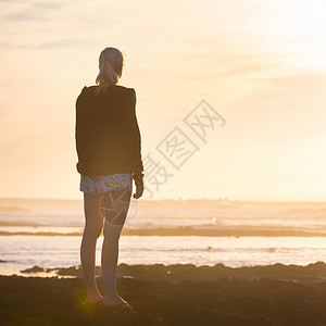 在沙滩上看日落的女人梦想家海洋冥想沉思成人地平线女士太阳阴影假期背景图片