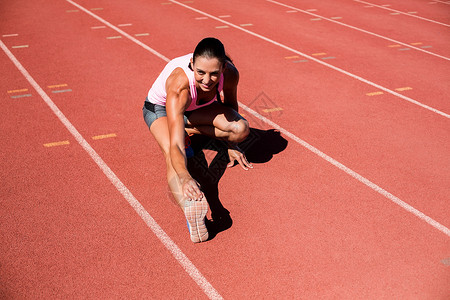 女性运动员伸展腿腕的肖像运动运动鞋竞赛体育场能力轨道挑战力量活力赛跑者背景图片