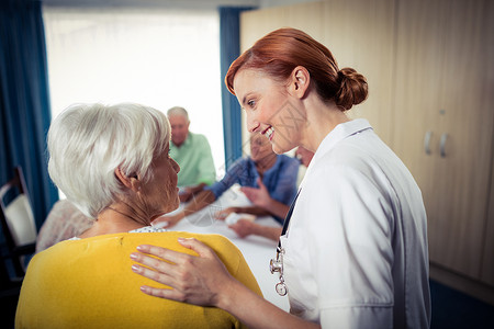 与护士打牌的养恤金领取者老年病医疗保险退休沟通女性帮助庇护所活动服务女士背景图片