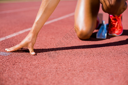 女运动员准备在赛道上运行运动鞋女性晴天赛跑者轨道起跑线专注运动服位置体育场背景图片