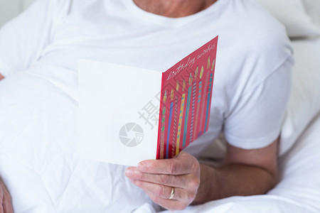 持有生日贺卡的高级男子老年男士退休问候男人医院卡片睡衣老年人病人背景图片