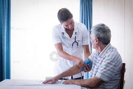 检查老年男子血液血压的女医生男人客厅桌子家庭保健互动治疗沟通指导服务背景图片