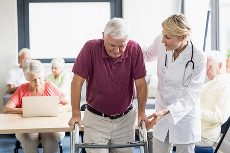 护士帮助老年人助学助行援助专注退休男性人员桌子技术医学女性医疗保险疗养院背景图片