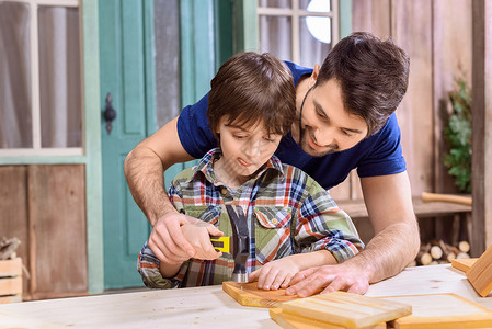 父亲教他如何用木板钉钉钉的画像 教集中的儿子童年领班成人男生锤击家庭木工工匠木匠男人背景图片