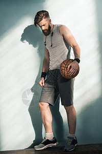 侧视图 wof 沉思的运动型男人手里拿着篮球背景图片