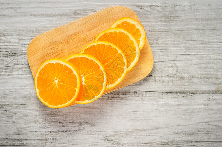 白木背景上的新鲜橙子切片水果砧板圆形热带食物木板白色宏观背景图片
