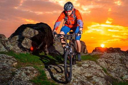 赛车手在美丽的日落山边骑着 极具活力的运动和冒险概念 的自行车下春落雪山娱乐运动员头盔速度男人成人天空岩石山地车下坡背景图片