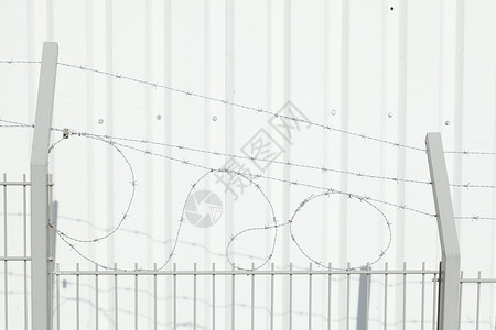 有刺带铁丝网的栅栏围栏白色工厂金属背景图片